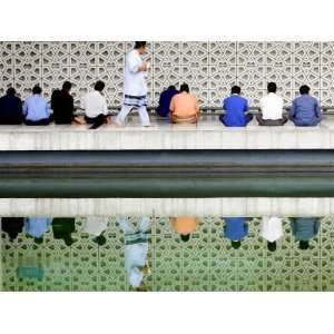 Reflection, a Muslim Man Walks Past Others Offering the Friday Prayer 